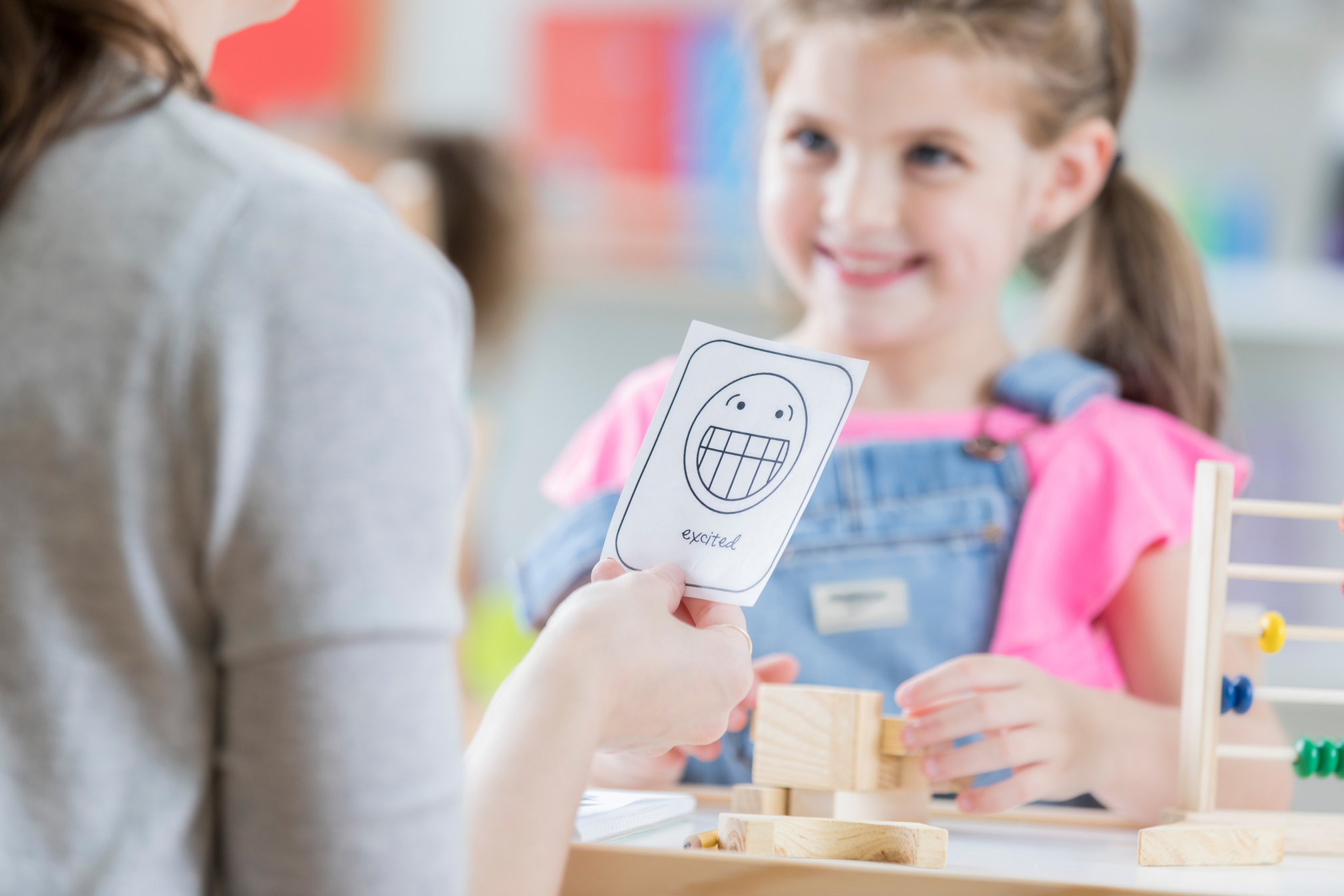 Teacher reviews emotion flashcards with young student